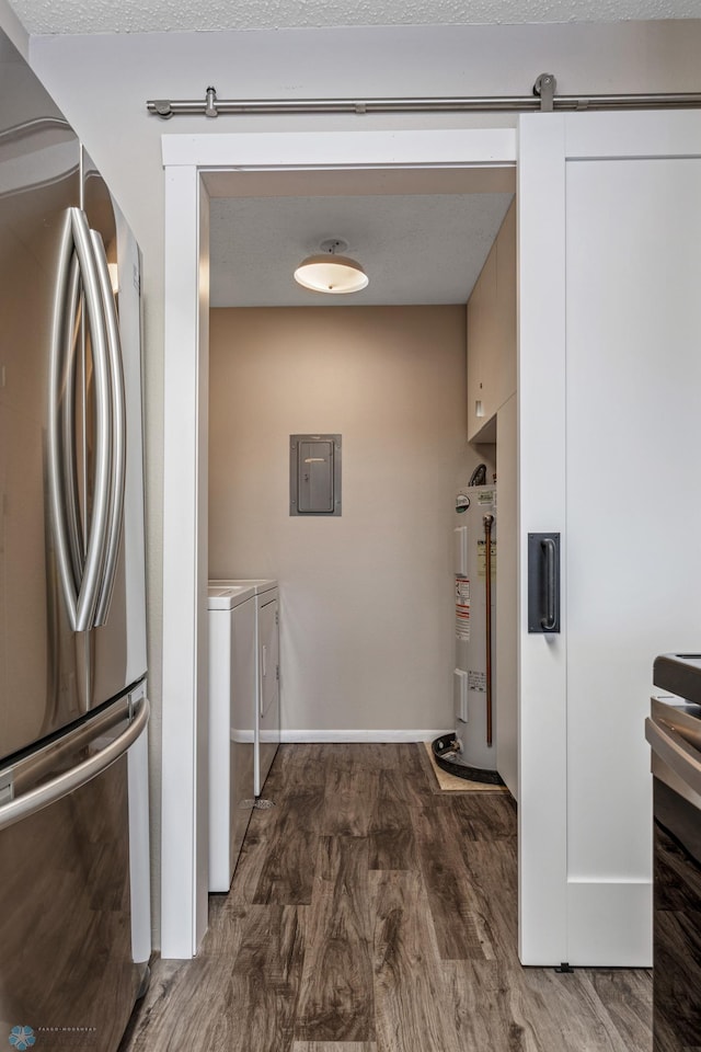 kitchen featuring washing machine and dryer, dark hardwood / wood-style flooring, electric water heater, stainless steel refrigerator, and a barn door