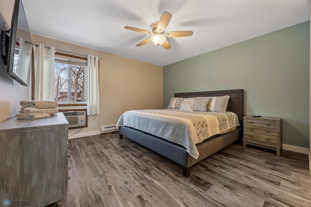 bedroom featuring ceiling fan, a wall mounted AC, a baseboard heating unit, hardwood / wood-style flooring, and a textured ceiling