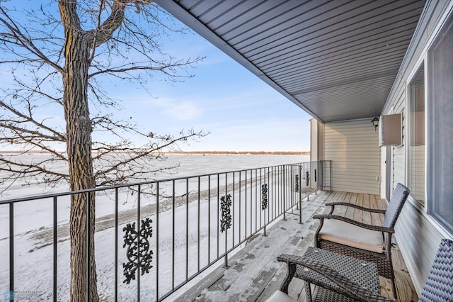 snow covered back of property featuring a water view