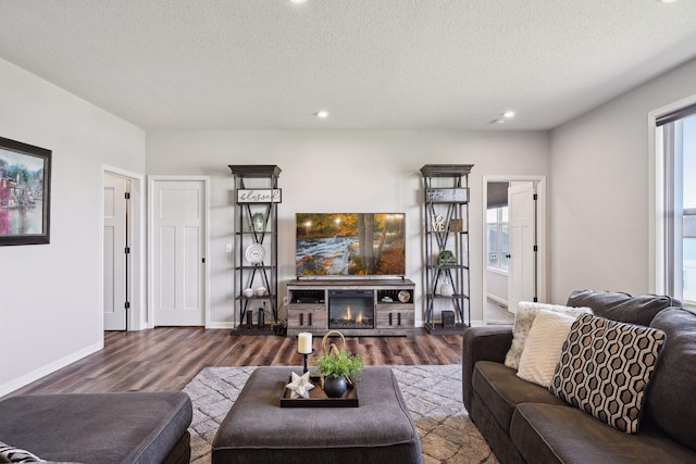 living area with recessed lighting, dark wood-type flooring, baseboards, and a textured ceiling
