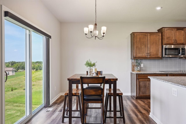 dining room with dark wood-style flooring, a notable chandelier, and a wealth of natural light
