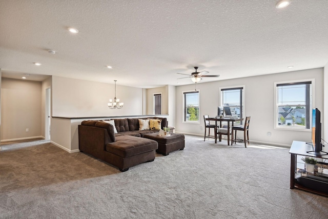 living room featuring ceiling fan with notable chandelier, carpet flooring, and baseboards