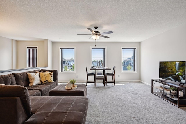 carpeted living room with baseboards, a textured ceiling, and ceiling fan