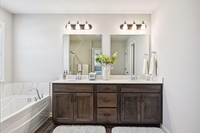 bathroom featuring double vanity, a garden tub, a sink, and wood finished floors