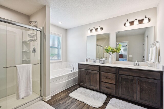 ensuite bathroom with a shower stall, a bath, a sink, and wood finished floors