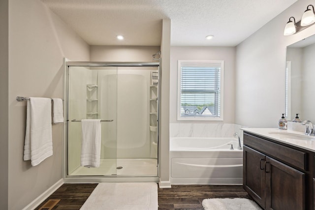 bathroom featuring a bath, a textured ceiling, vanity, wood finished floors, and a stall shower