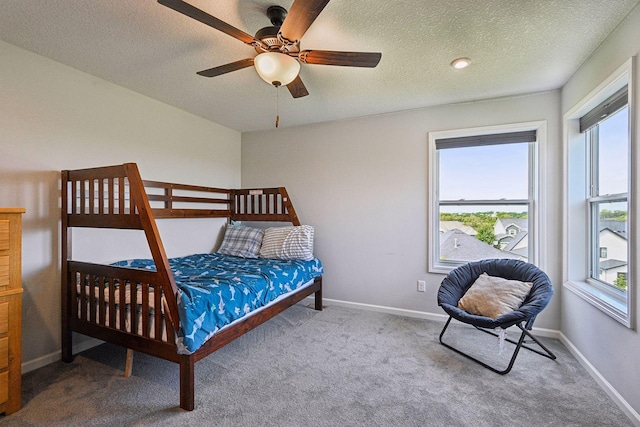 bedroom with a textured ceiling, baseboards, a ceiling fan, and carpet