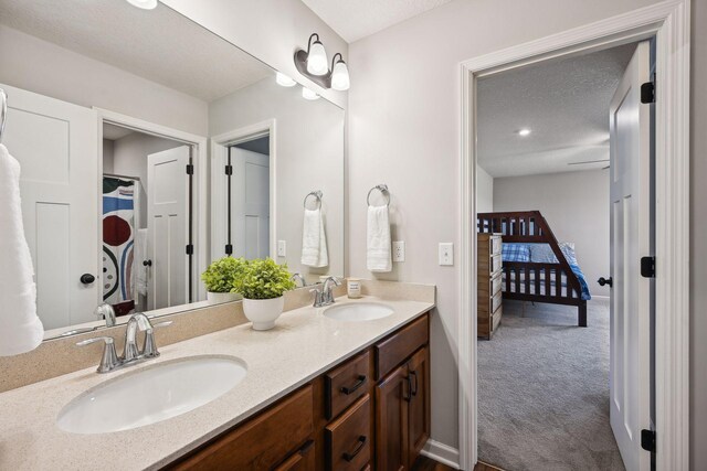 bathroom featuring double vanity, a sink, baseboards, and ensuite bath