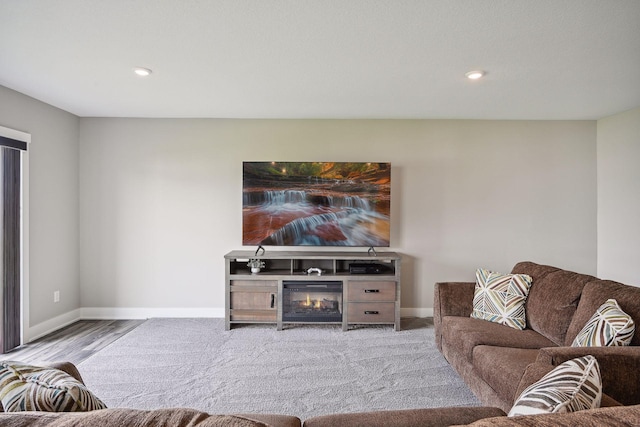 living room featuring baseboards, a glass covered fireplace, and recessed lighting
