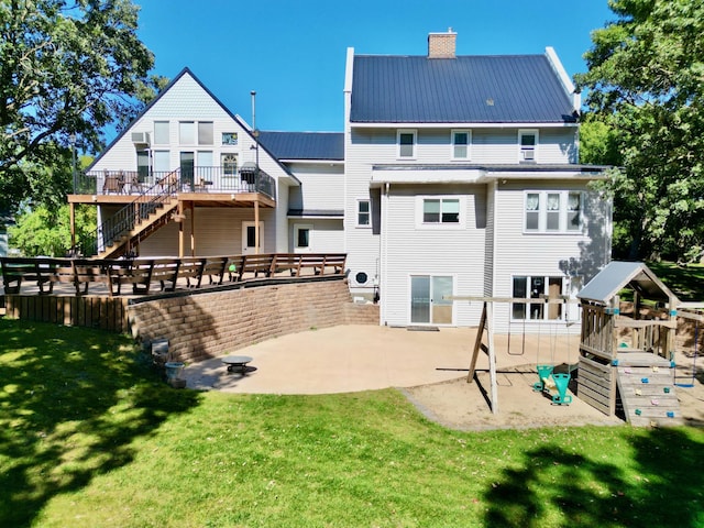 back of property featuring a deck, a patio area, and a lawn