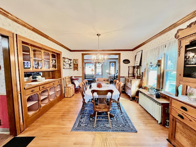 dining area featuring radiator, crown molding, light hardwood / wood-style flooring, and a notable chandelier