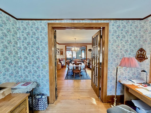 hall with french doors, light hardwood / wood-style floors, an inviting chandelier, and ornamental molding