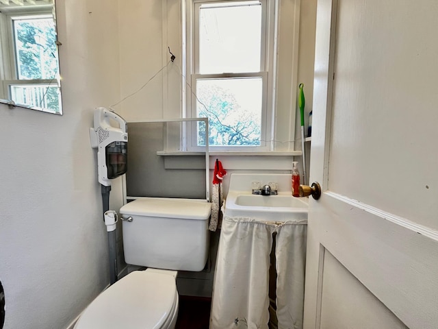 bathroom featuring heating unit, a wealth of natural light, sink, and toilet