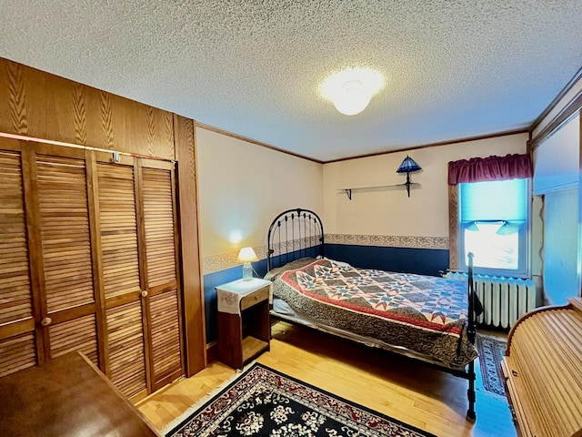 bedroom featuring radiator heating unit, a textured ceiling, hardwood / wood-style flooring, and a closet