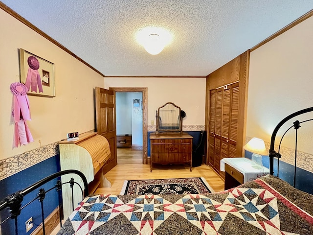 bedroom with light wood-type flooring, a textured ceiling, a closet, and crown molding