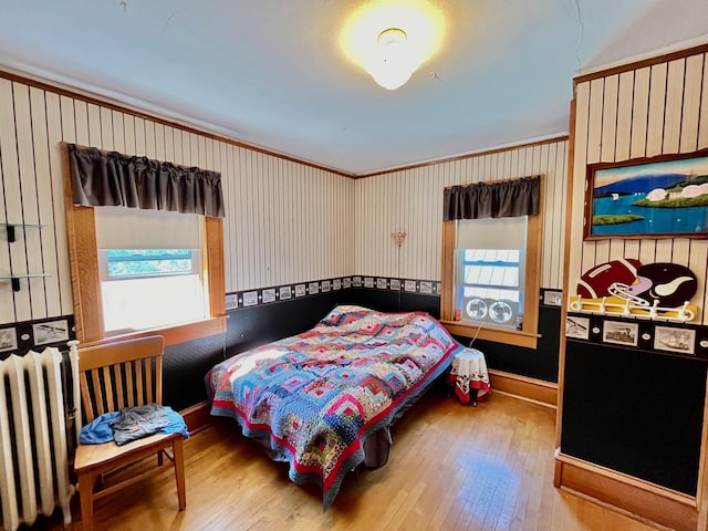 bedroom featuring hardwood / wood-style flooring, radiator, and ornamental molding