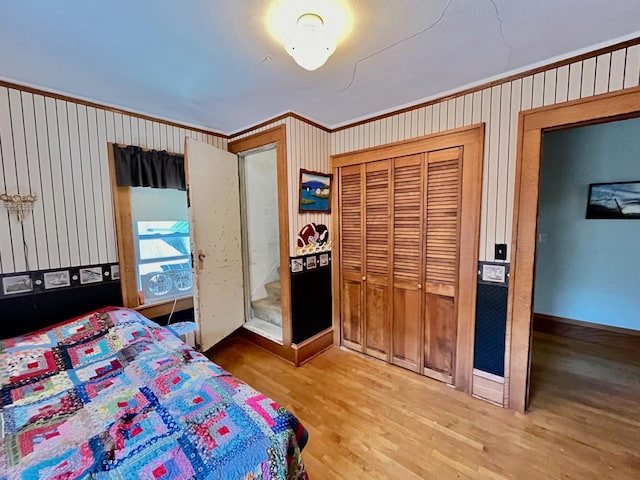 bedroom with a closet, hardwood / wood-style floors, and ornamental molding