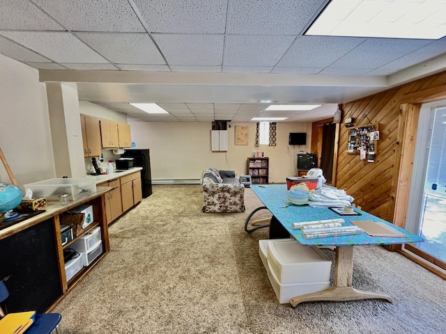 carpeted dining room with baseboard heating, wood walls, and a drop ceiling