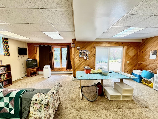 playroom with carpet, a drop ceiling, and wood walls