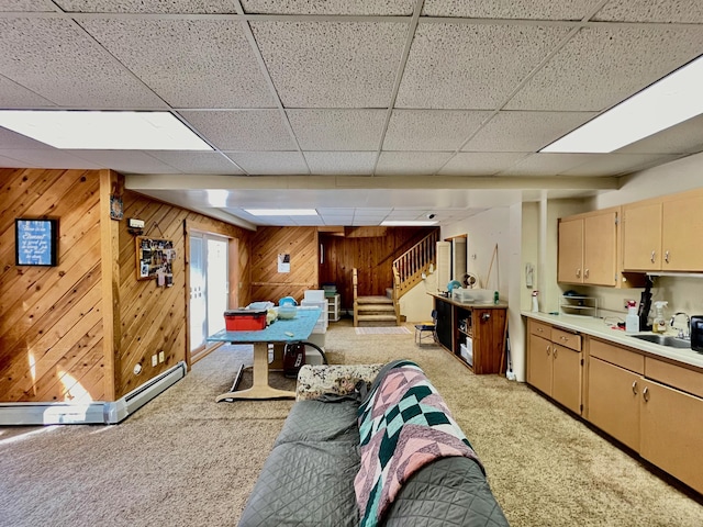 playroom with light carpet, a paneled ceiling, a baseboard heating unit, sink, and wood walls