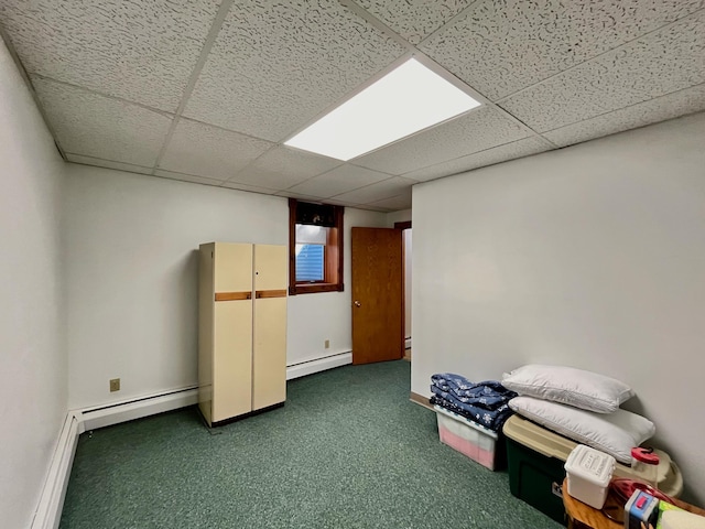 interior space featuring dark colored carpet, a drop ceiling, and a baseboard heating unit