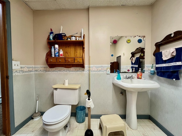 bathroom featuring a paneled ceiling, toilet, and tile patterned floors