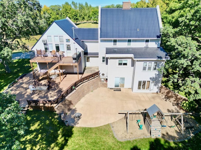 rear view of property featuring a playground, a deck, and a lawn