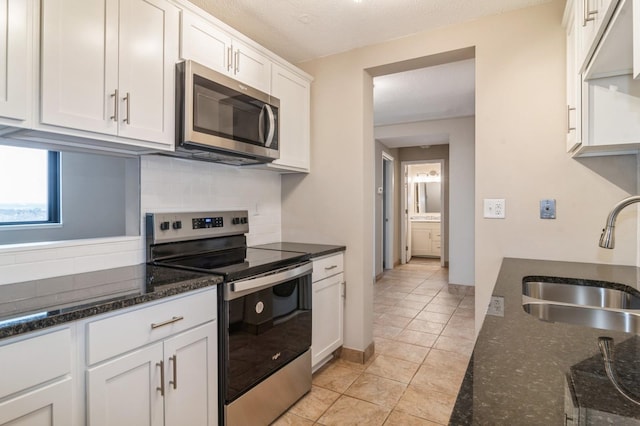 kitchen with white cabinets, sink, appliances with stainless steel finishes, and dark stone counters