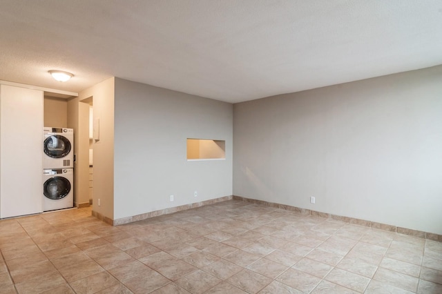 unfurnished room featuring a textured ceiling and stacked washer / drying machine