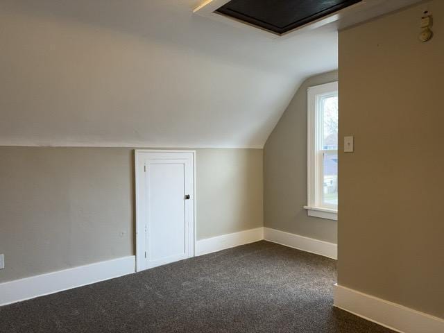 additional living space featuring dark carpet and vaulted ceiling