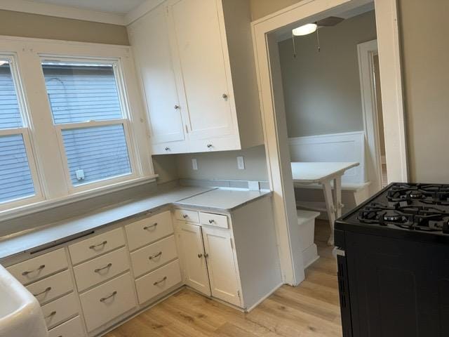 kitchen featuring white cabinetry, light hardwood / wood-style flooring, and black range