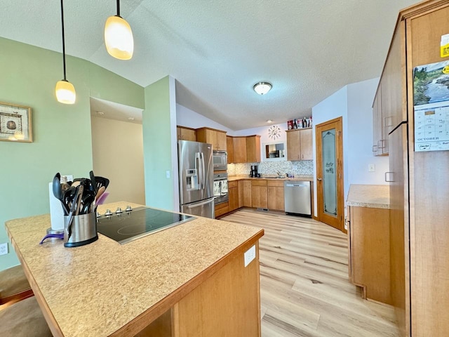 kitchen with tasteful backsplash, kitchen peninsula, vaulted ceiling, decorative light fixtures, and appliances with stainless steel finishes