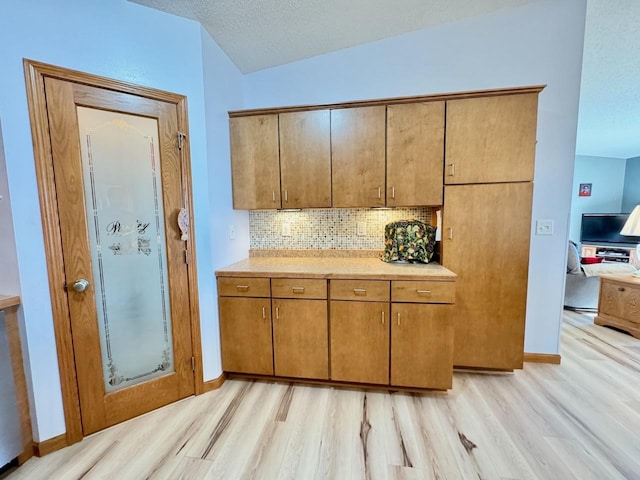 kitchen with decorative backsplash, a textured ceiling, and light hardwood / wood-style flooring