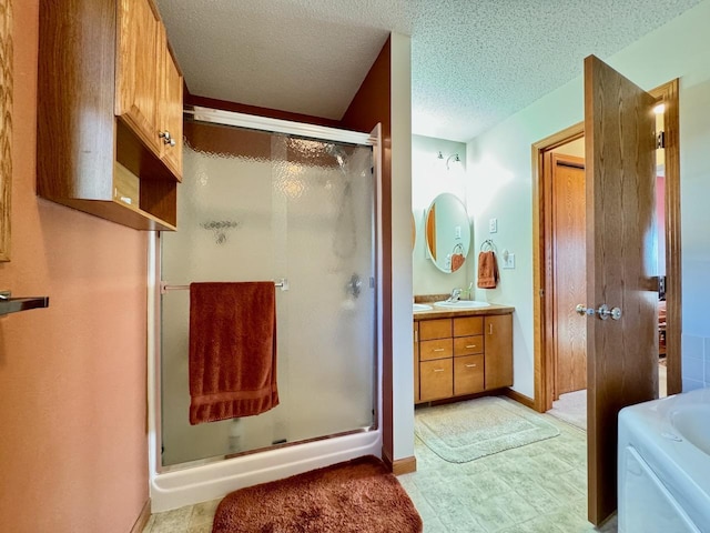 bathroom with vanity, a shower with shower door, and a textured ceiling