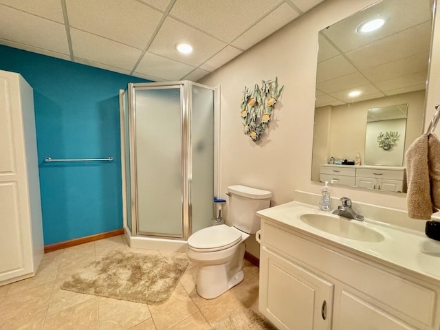 bathroom featuring toilet, a drop ceiling, vanity, and walk in shower