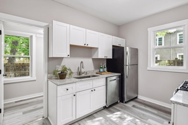 kitchen featuring sink, white cabinets, light wood-type flooring, and appliances with stainless steel finishes