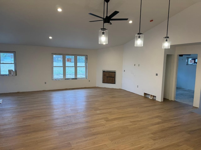 unfurnished living room featuring ceiling fan, vaulted ceiling, and light wood-type flooring