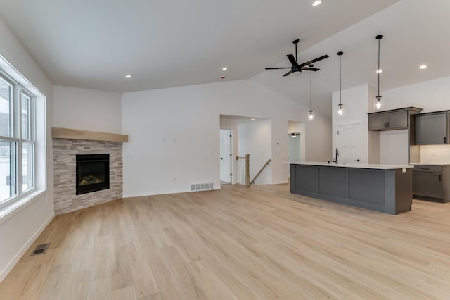 unfurnished living room featuring lofted ceiling, a sink, visible vents, and light wood-style floors