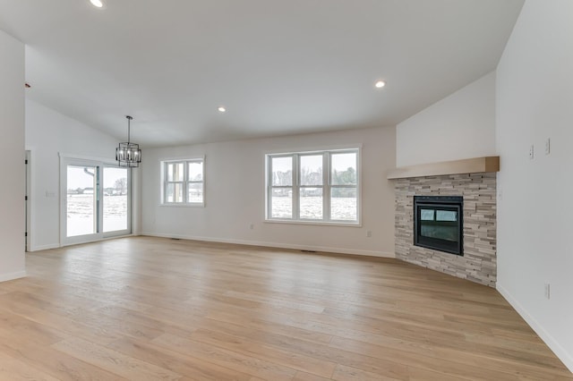 unfurnished living room featuring recessed lighting, an inviting chandelier, light wood-style floors, a stone fireplace, and baseboards