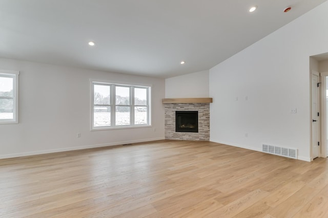 unfurnished living room with light wood finished floors, baseboards, visible vents, a stone fireplace, and recessed lighting