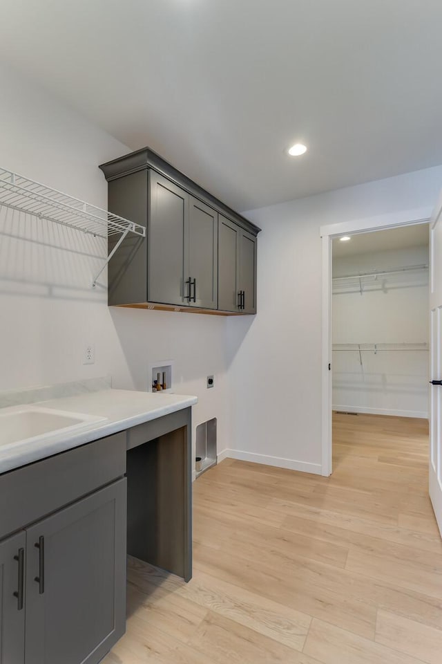 washroom featuring light wood-style floors, washer hookup, cabinet space, and electric dryer hookup