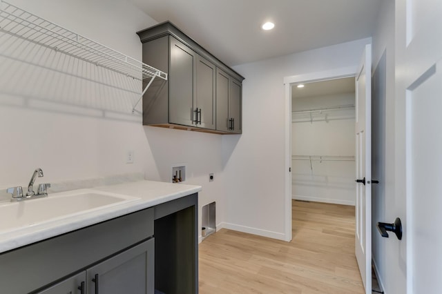 laundry area with hookup for a washing machine, cabinet space, light wood-style flooring, electric dryer hookup, and baseboards