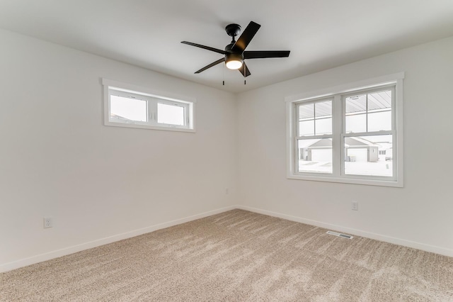 carpeted spare room with a ceiling fan, visible vents, and baseboards