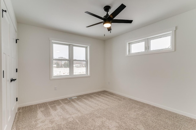 carpeted spare room with ceiling fan, baseboards, and a wealth of natural light