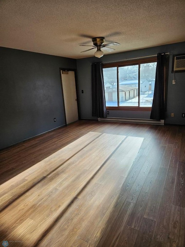 spare room featuring a wall mounted air conditioner, a textured ceiling, baseboard heating, ceiling fan, and hardwood / wood-style flooring