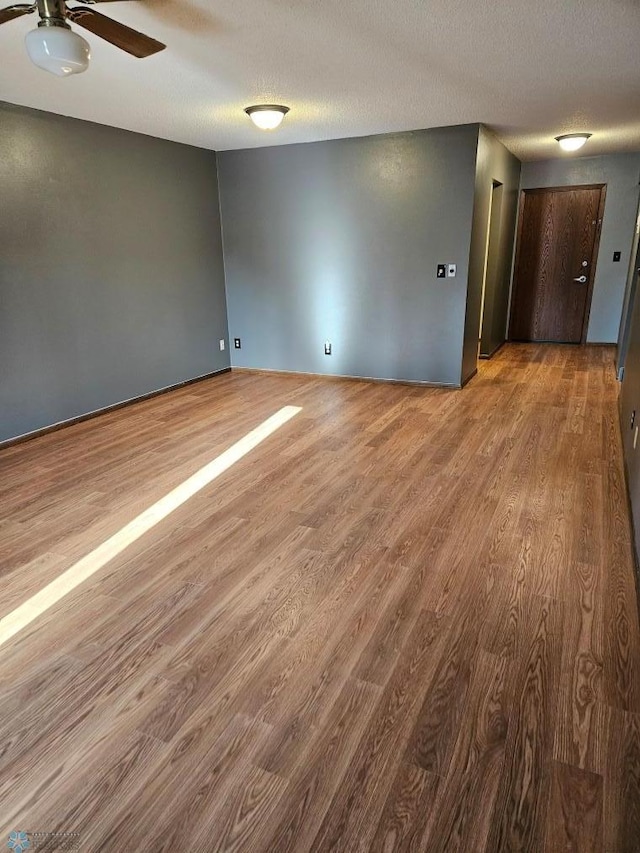 unfurnished room featuring a textured ceiling, a ceiling fan, and wood finished floors