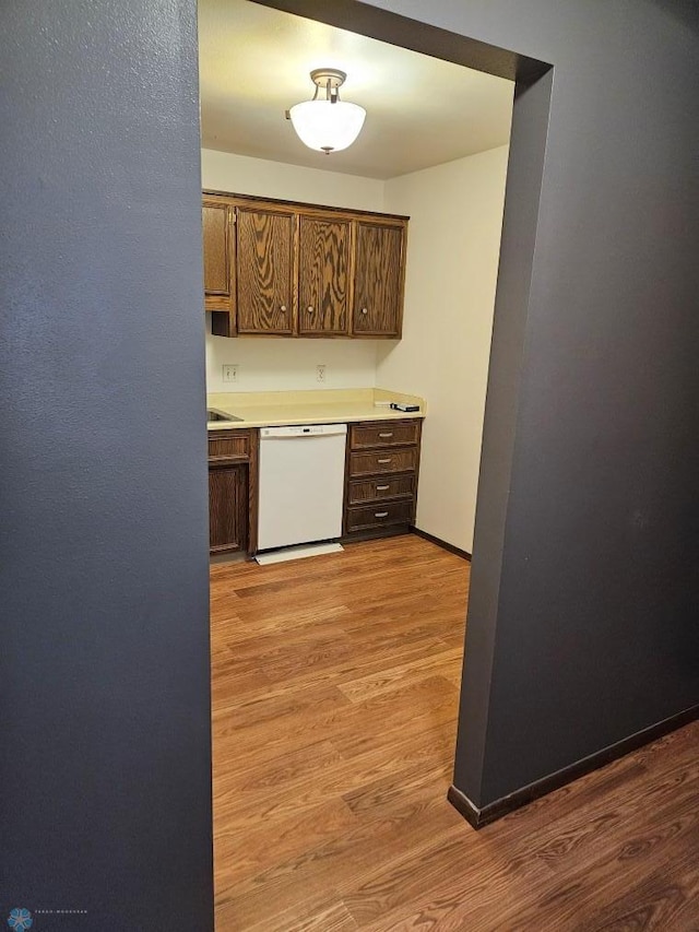 kitchen featuring dishwasher, light countertops, baseboards, and light wood finished floors