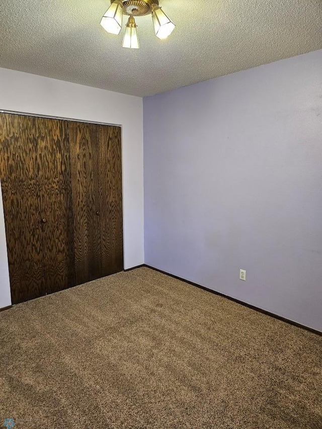 unfurnished bedroom with carpet, a textured ceiling, and a closet