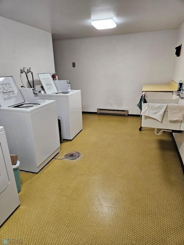 washroom with light carpet, baseboard heating, and washing machine and clothes dryer