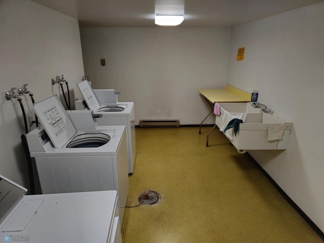 clothes washing area with washing machine and dryer, a baseboard heating unit, and baseboards